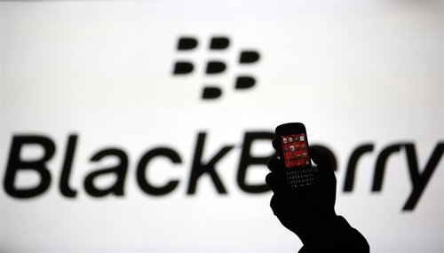 La silueta de un hombre que sostiene un teléfono Q10 de BlackBerry frente a una 