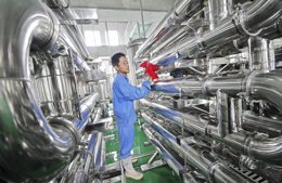 Un empleado limpia unos equipos en una fábrica de vinos en Weifang, China, j