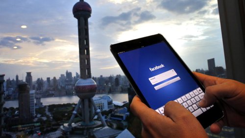 Un hombre sostiene un iPad con la aplicación de Facebook en un edificio de ofici