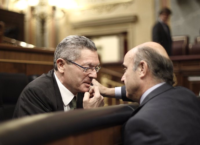 Alberto Ruiz Gallardón y Luis De Guindos hablando en el hemiciclo