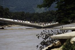 Habitantes de Coyuca cruzan un puente afectado por el huracán 'Manuel'. 