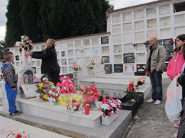 Una familia decora con flores la lápida de un ser querido. 
