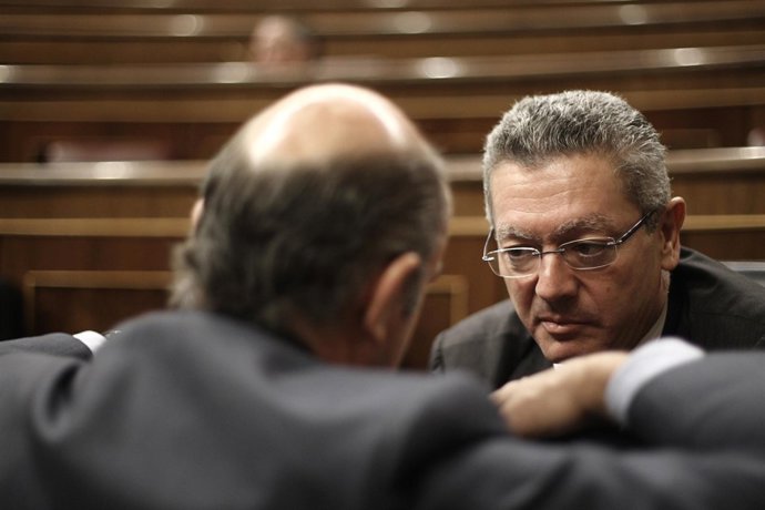 Alberto Ruiz Gallardón y Luis De Guindos hablando en el hemiciclo