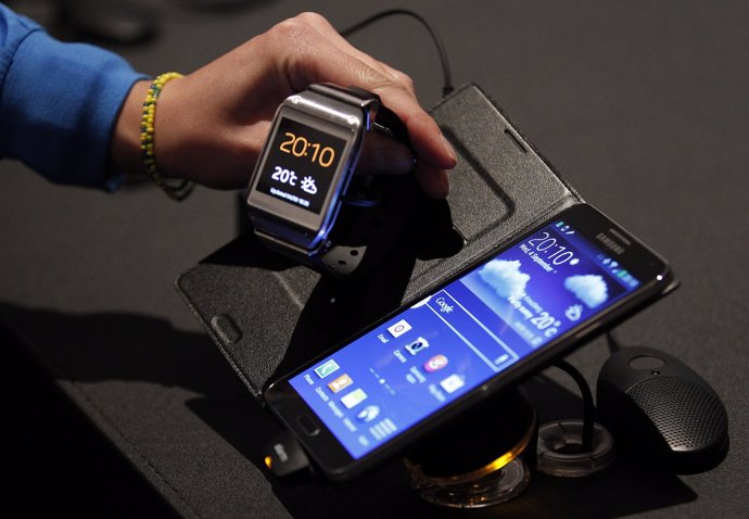 Un periodisa observa el reloj Galaxy Gear de Samsung junto a un teléfono Galaxy 