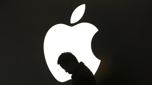 Un hombre revisa su iPad frente a un logo de Apple en las afueras de una tienda 