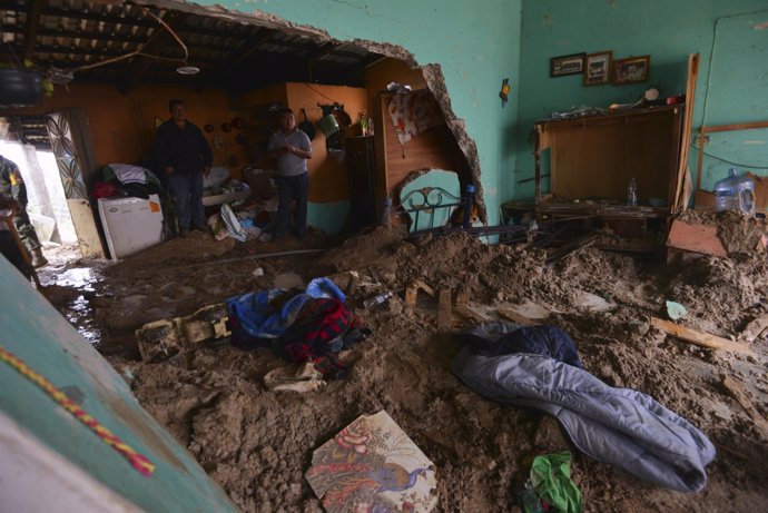 Un grupo de personas reunidas en una casa inundada por barro