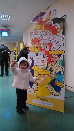 Una niña echa su carta a los Reyes Magos en un buzón de Correos