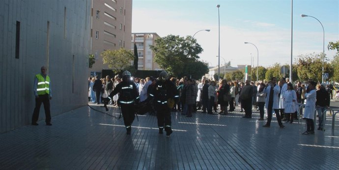 Usuarios y personal del centro evacuados observan la actuación de los bomberos