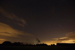 A Perseid meteor streaks across the sky over the Lovell Radio Telescope at Jodre