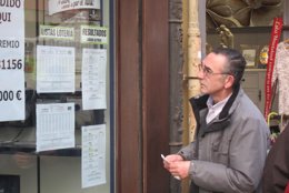 Un hombre comprobando los números premiados en la Lotería