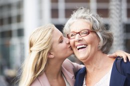 Teenage girl kissing smiling grandmother