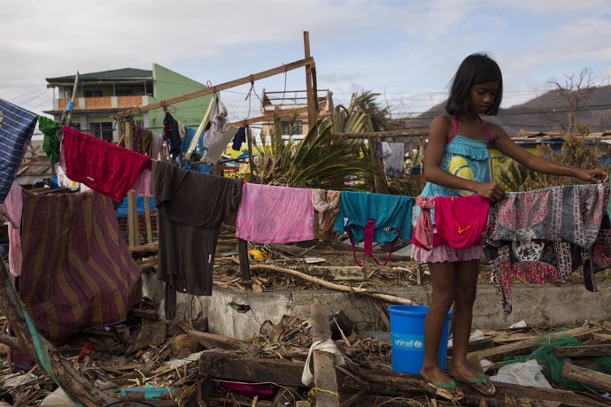 A girl made homeless by Haiyan Typhoon hangs washing on a line outside a displac