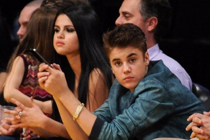 LOS ANGELES, CA - APRIL 17:  Justin Beiber and girlfriend Selena Gomez watch the