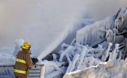 A firefighter sprays water at the Residence du Havre after a fire in L'Isle Vert