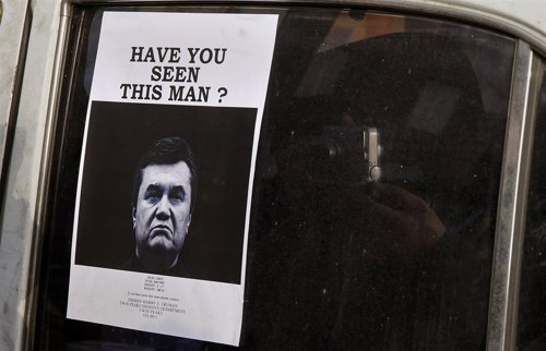 Un hombre fotografía un cartel en el que se busca a Yanukovich