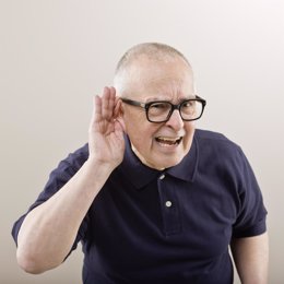 Hombre mayor tratando de escuchar con la mano en el oído