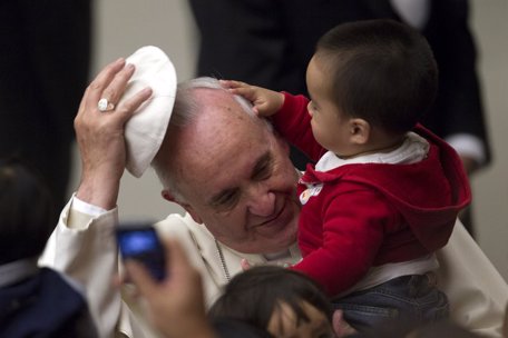 Pope Francis has his skull cap removed by a child during an audience with childr