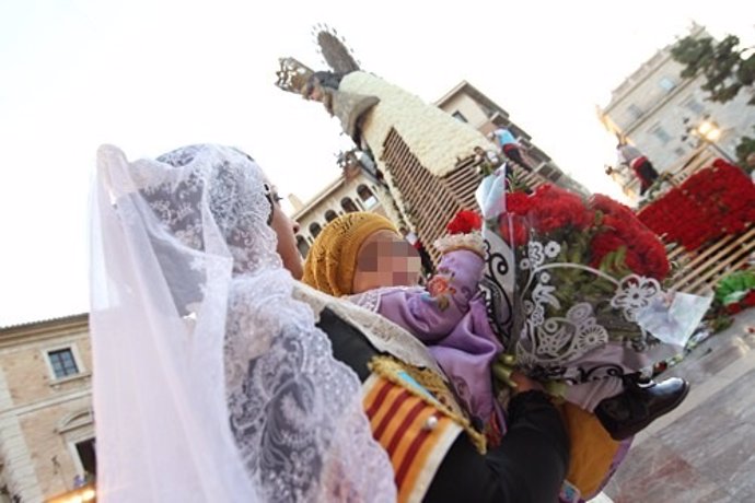 Una fallera y un bebé pasan ante la imagen de al Virgen en la Ofrenda 