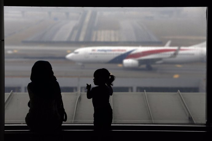 Una mujer y una niña miran un avión de Malaysia Airlines
