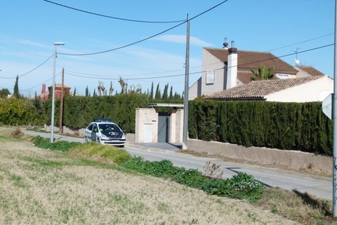 Un coche de la Policía Local de Murcia pasa por una viivienda en la huerta