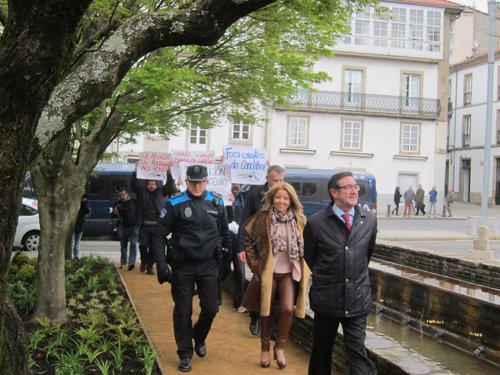 El alcalde de Santiago y la edila Reyes Leis, seguidos por una protesta