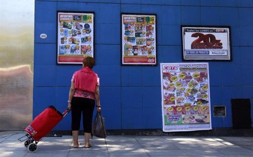 Una mujer observa los carteles con productos en venta en un supermercado