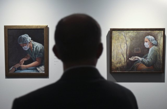 Un visitante observa cuadros de la exposición 'Luz en Hipocratia' de Emma Cano