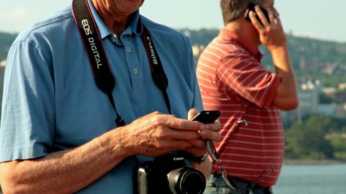 Turista en la playa con cámara y teléfono móvil smartphone verano vacaciones