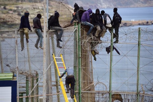 Inmigrantes encaramados a la valla en Melilla