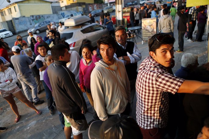 People line up outside a store after an earthquake and tsunami hit the northern 
