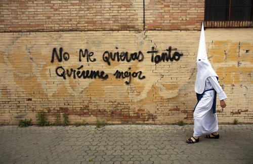 Un penitente camina al lado de un grafiti