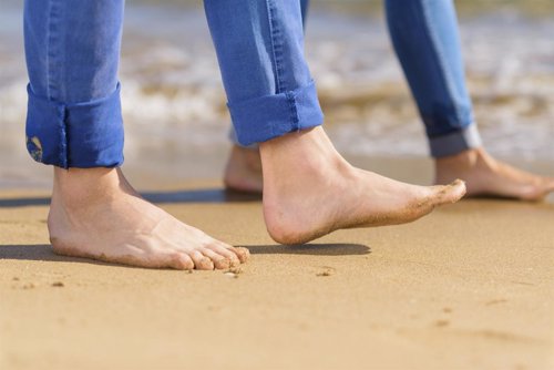 Pareja con los pies descalzos paseando por la playa