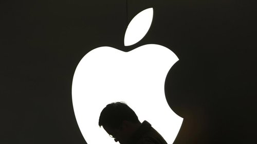 Hombre usando iPad frente al logotipo de Apple