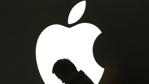 Hombre usando iPad frente al logotipo de Apple