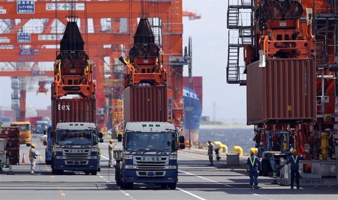 Trabajadores cargan contenedores en una embarcación en el puerto de Tokio