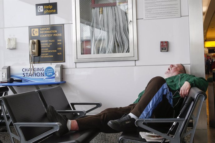 A man sleeps in a waiting area of the central terminal of LaGuardia Airport in t