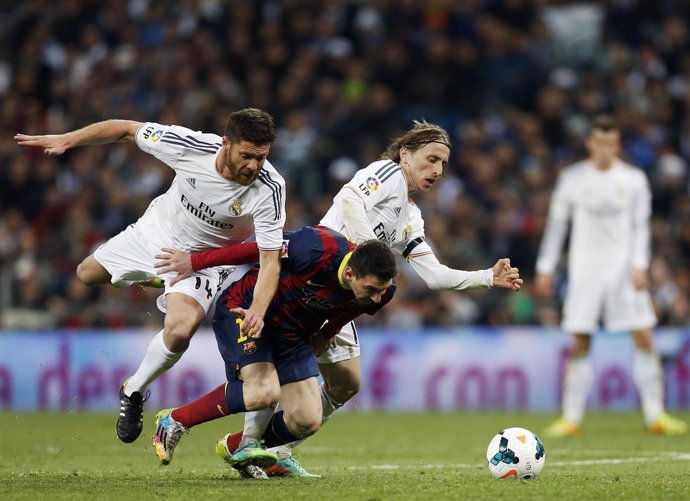 Xabi Alonso y Modric pelean un balón con Leo Messi