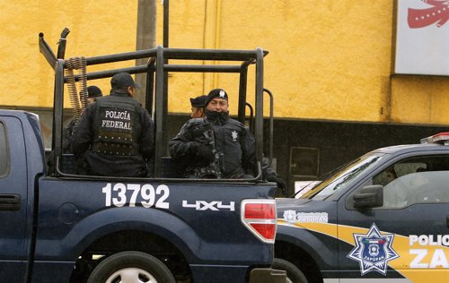 Mexican federal police ride in a vehicle as they patrol on a main avenue in Guad