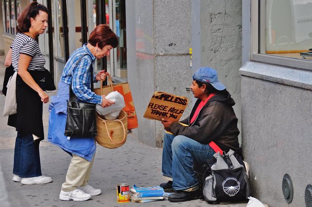 Mujer dando comida a indigente en Broadway