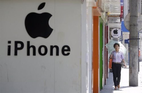 Una mujer camina junto a un logo de Apple en Wuhan, provincia de Hubei, China