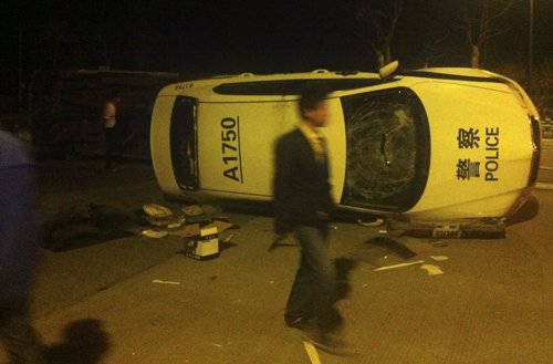 Manifestante pasa ante un coche destrozado por los enfrentamientos en China