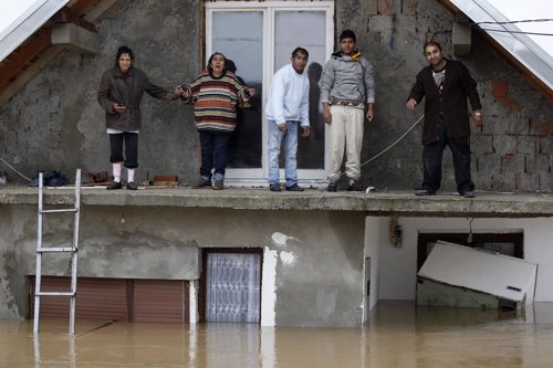 People stand on a terrace of their flooded house as the wait to be evacuated in 