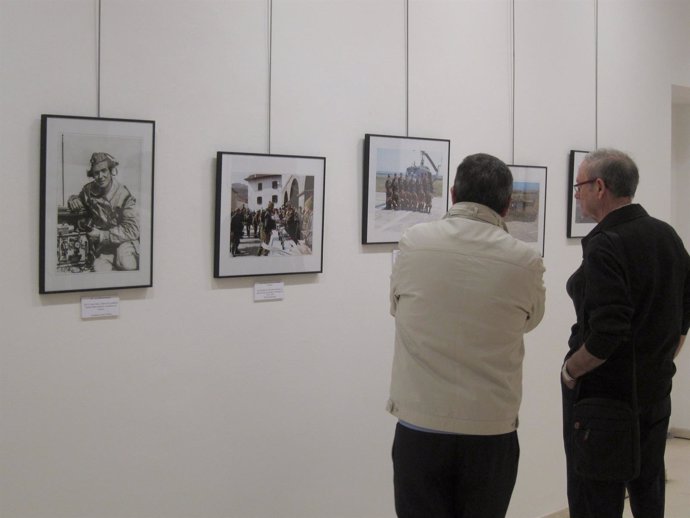 Dos visitantes observan la muestra, con una foto del Rey a un lado