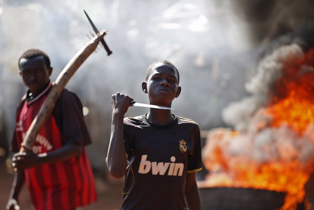 A boy gestures in front of a barricade on fire during a protest after French tro