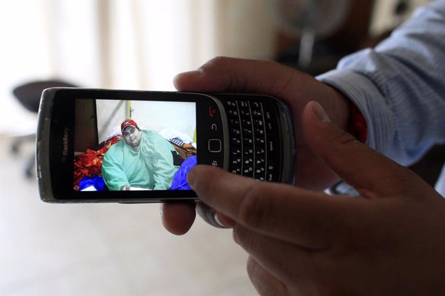 Relative of late Manuel Uribe shows a picture of him in his mobile phone at his 
