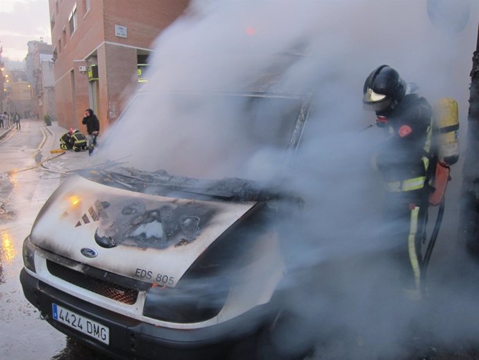 Un bombero extinge el fuego de una unidad de TV3 tras la marcha de Can Vies