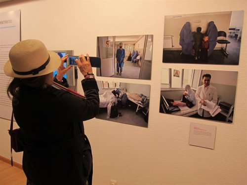 Una mujer fotografía con su móvil la exposición 'CooperaciónESdesarrollo'