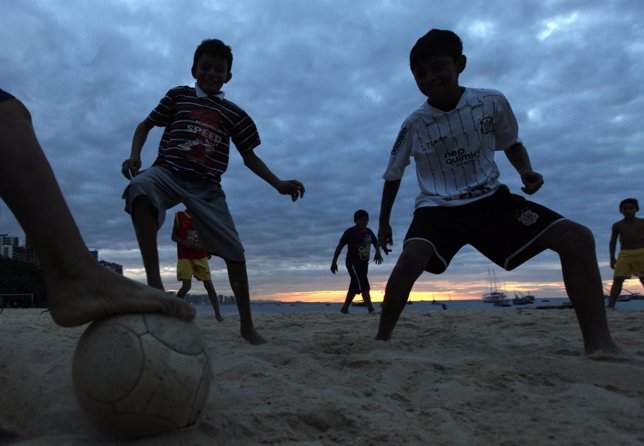 Niños brasileños jugando al fútbol en una playa brasileña.