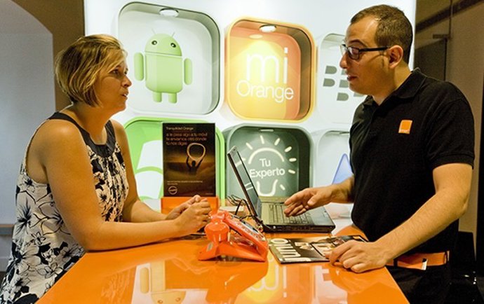 Asesor de Orange prestando ayuda a un cliente en una tienda de la operadora
