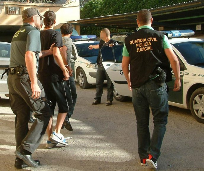 Guardias civiles realizan el traslado de uno de los detenidos